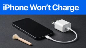 An iPhone connected to a charger beside a small cleaning brush.
